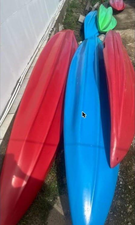 Kayaks rouges, bleu et vert rangés le long du mur de la pension