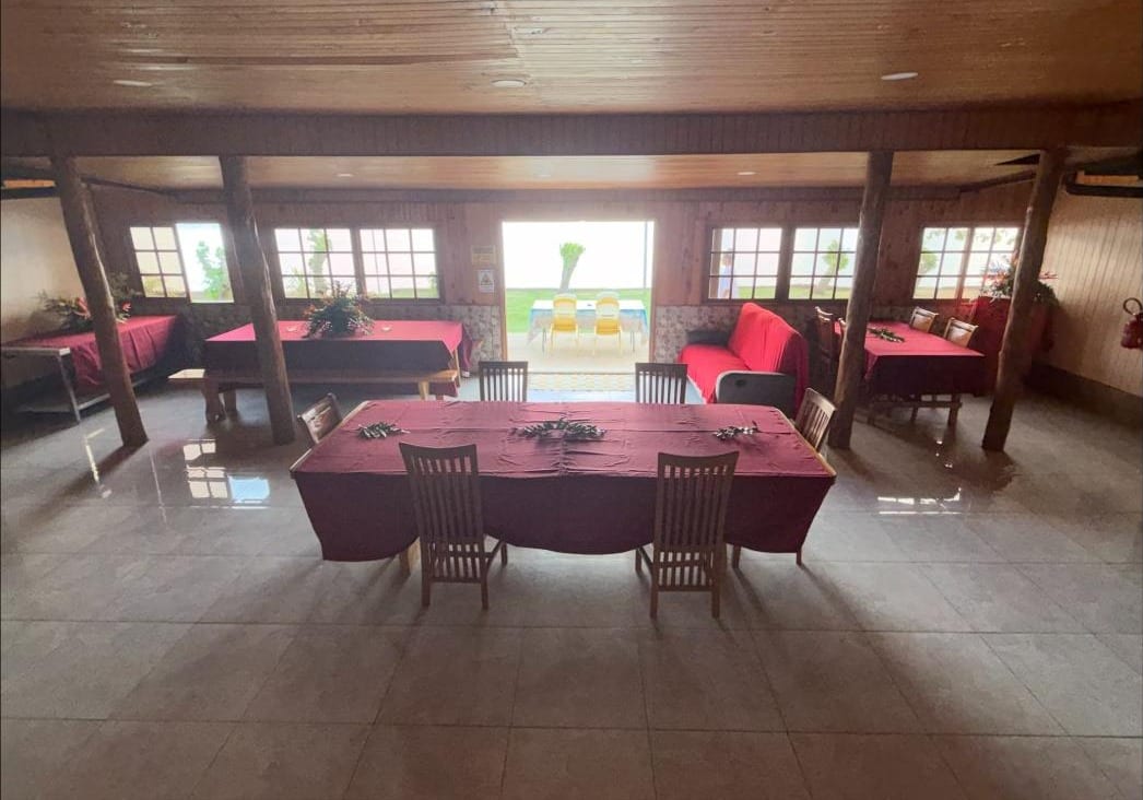 La grande salle à manger de la pension, tables nappées de bordeaux, ouverte vers la mer