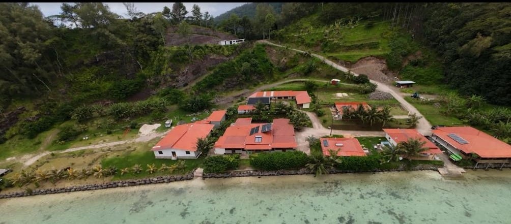 Vue aérienne au drone de la pension Kirimiro Beach : les toits rouges entre la colline et le lagon