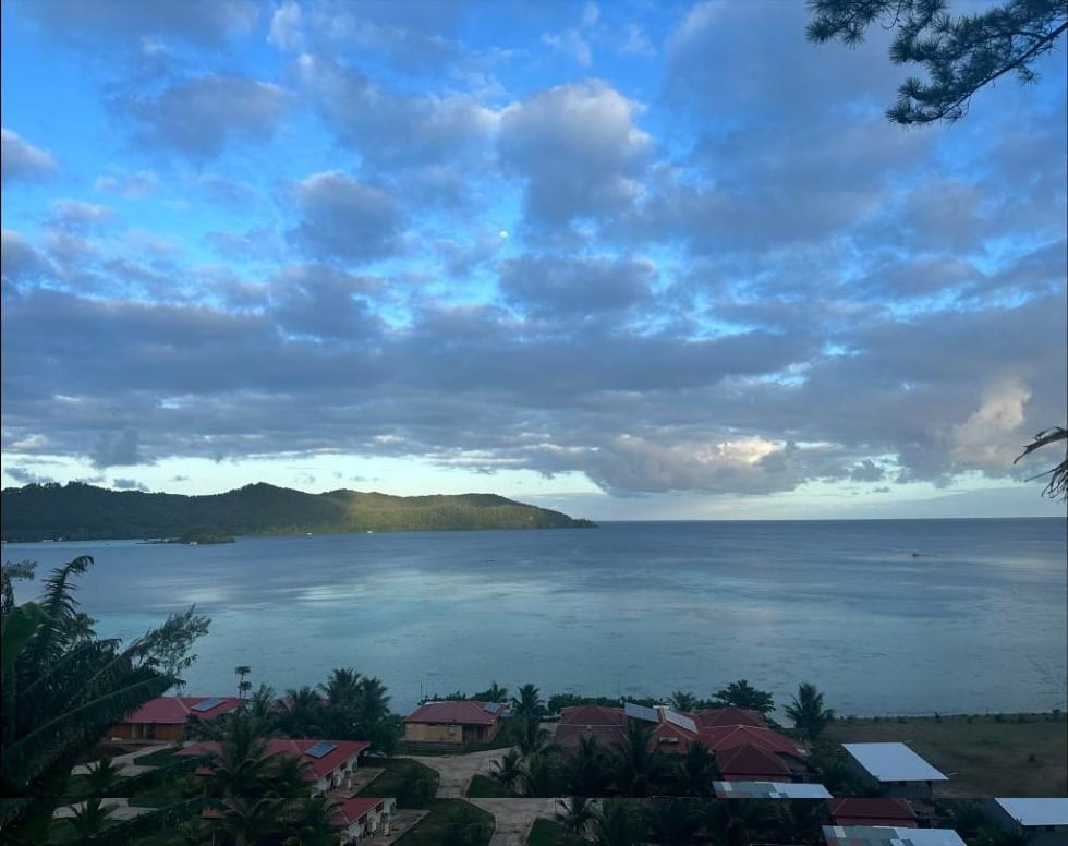 Vue depuis la colline : les toits rouges de la pension au bord du lagon de Mangareva